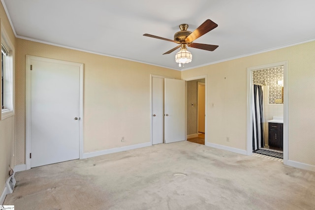 unfurnished bedroom with light carpet, ornamental molding, multiple closets, and ensuite bathroom