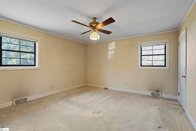 carpeted empty room featuring a wealth of natural light, ornamental molding, and ceiling fan