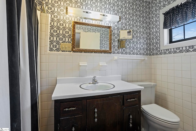 bathroom featuring vanity, tile walls, and toilet