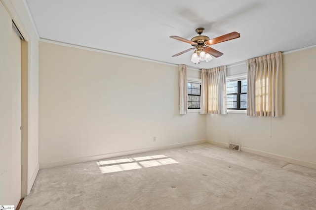 empty room with crown molding, light colored carpet, and ceiling fan