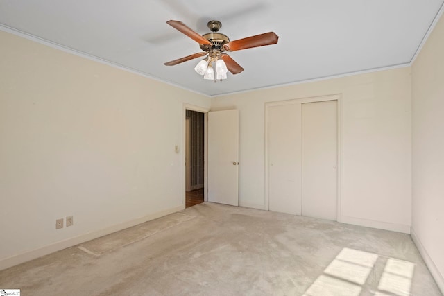 unfurnished bedroom with ornamental molding, light colored carpet, ceiling fan, and a closet