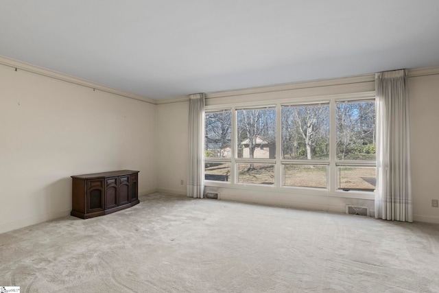 spare room with light carpet, plenty of natural light, and ornamental molding