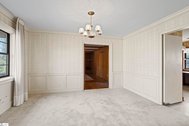 carpeted spare room with crown molding and a chandelier