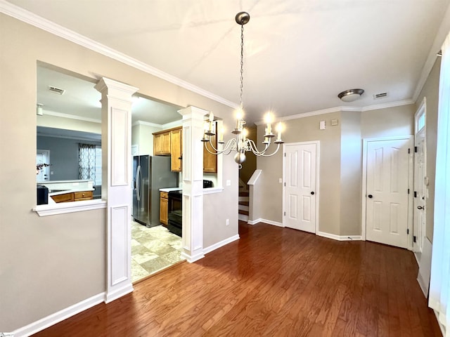 unfurnished dining area featuring a notable chandelier, crown molding, wood-type flooring, and ornate columns