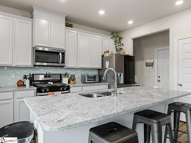 kitchen featuring an island with sink, appliances with stainless steel finishes, sink, and white cabinets