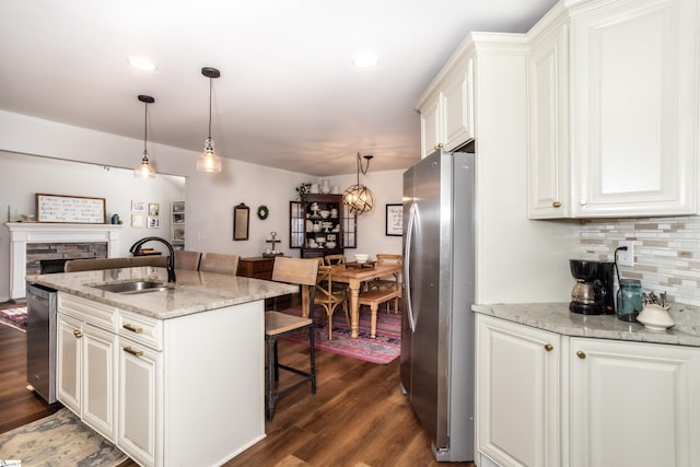 kitchen featuring stainless steel appliances, white cabinetry, hanging light fixtures, and sink