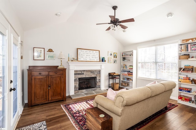 living room with vaulted ceiling, a stone fireplace, ceiling fan, and dark hardwood / wood-style flooring