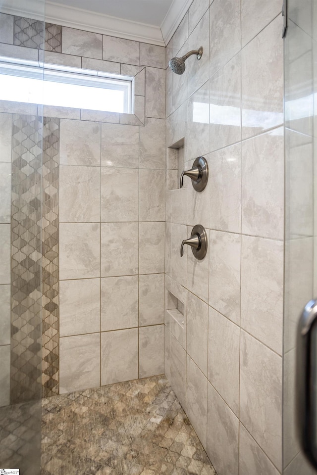 bathroom with ornamental molding and a tile shower