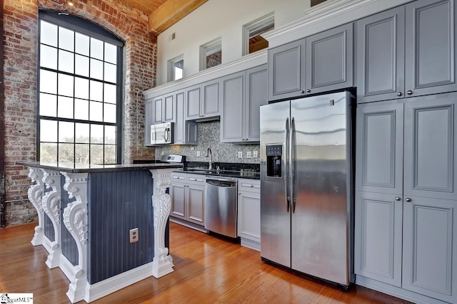 kitchen with a kitchen bar, gray cabinets, a healthy amount of sunlight, and appliances with stainless steel finishes