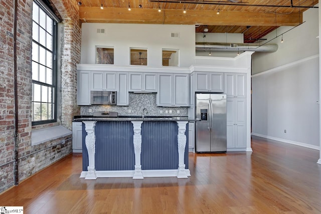 kitchen with wood ceiling, a breakfast bar area, stainless steel appliances, a center island, and a high ceiling