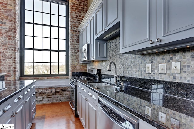 kitchen featuring dark stone countertops, sink, gray cabinets, and stainless steel appliances