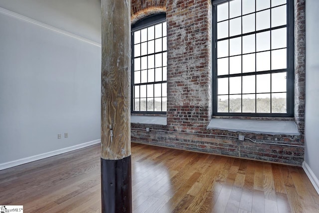 empty room featuring wood-type flooring and brick wall