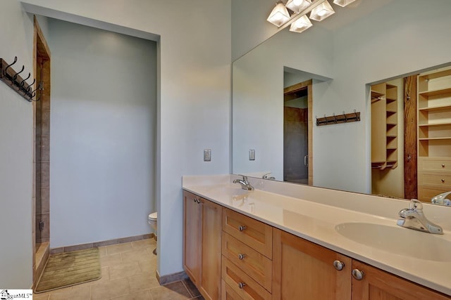 bathroom featuring a shower with door, vanity, tile patterned flooring, and toilet