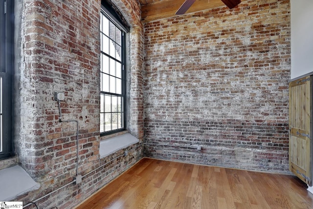 unfurnished room featuring light hardwood / wood-style floors and brick wall