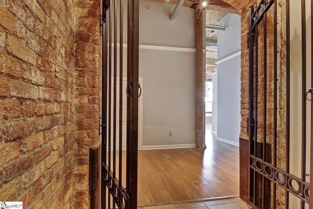 hall with hardwood / wood-style flooring and brick wall