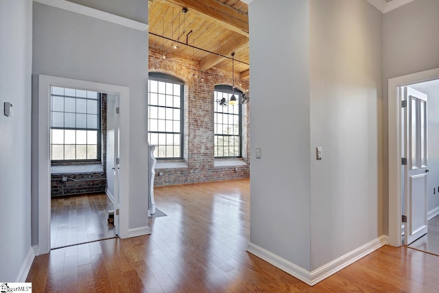 interior space featuring brick wall, hardwood / wood-style floors, wooden ceiling, and beam ceiling