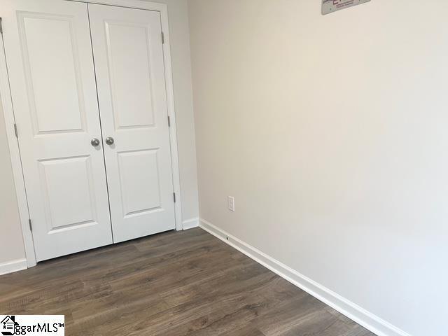 unfurnished bedroom featuring dark hardwood / wood-style floors and a closet