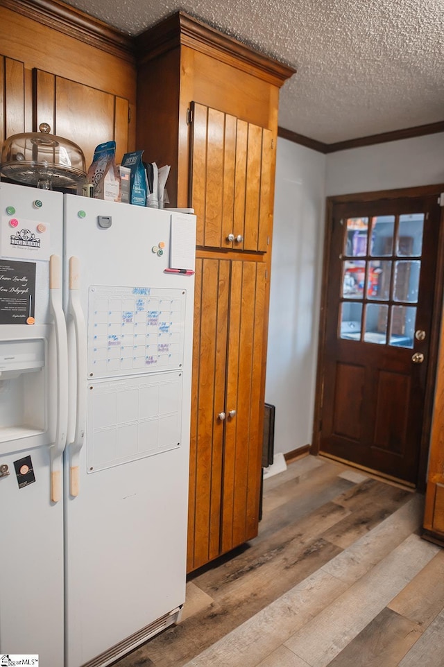 kitchen with crown molding, light hardwood / wood-style floors, white fridge with ice dispenser, and a textured ceiling