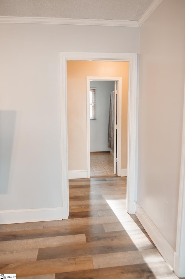 hall with ornamental molding and light hardwood / wood-style floors