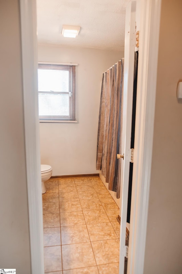 bathroom with toilet, tile patterned flooring, and a textured ceiling