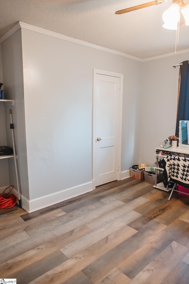 interior space featuring crown molding, wood-type flooring, a textured ceiling, and ceiling fan