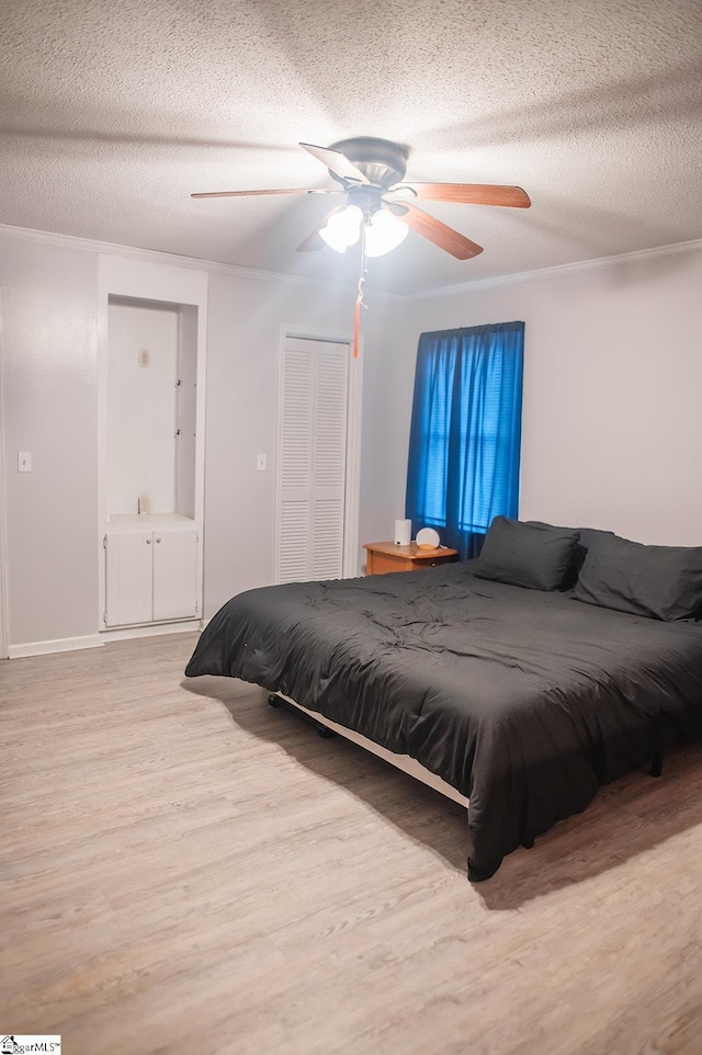 bedroom with light wood-type flooring, ceiling fan, crown molding, a textured ceiling, and a closet