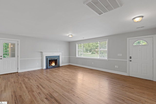 unfurnished living room with hardwood / wood-style floors and a brick fireplace