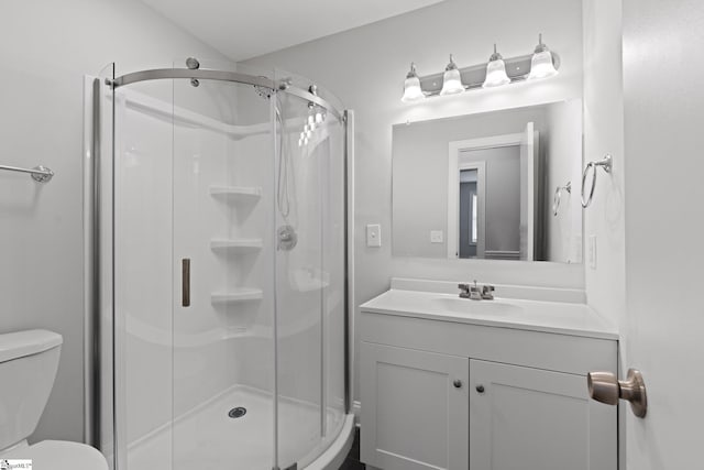 bathroom with vanity, a shower with door, and toilet