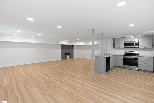 kitchen featuring sink, gray cabinetry, light hardwood / wood-style flooring, stainless steel appliances, and decorative backsplash