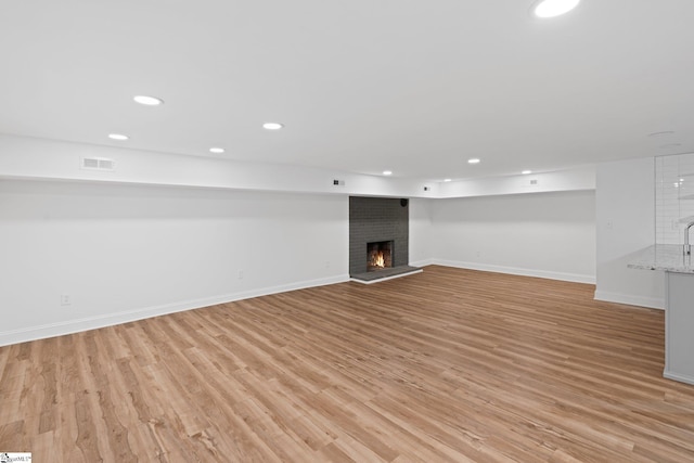 basement featuring a brick fireplace and light hardwood / wood-style floors