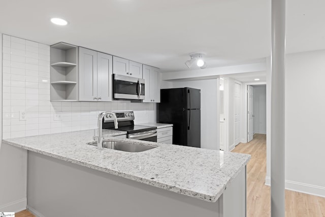 kitchen featuring backsplash, light stone countertops, kitchen peninsula, and appliances with stainless steel finishes