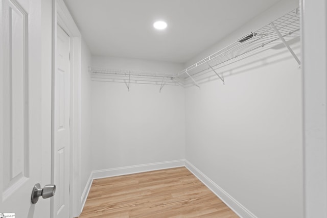 walk in closet with hardwood / wood-style flooring