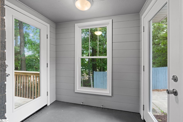 doorway to outside featuring concrete flooring and wood walls