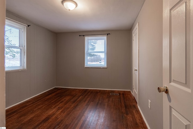 empty room featuring plenty of natural light and dark wood-type flooring