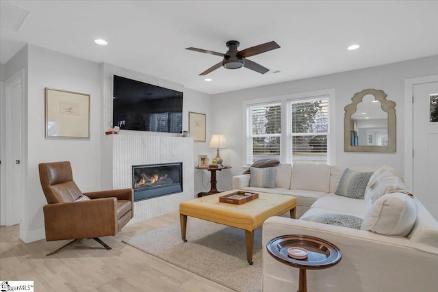 living room with a fireplace, light hardwood / wood-style floors, and ceiling fan