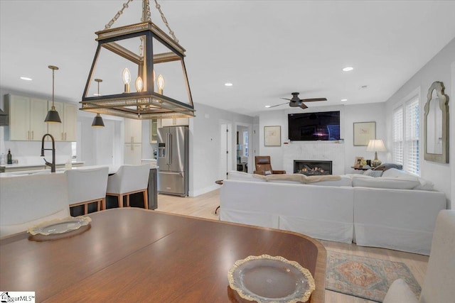 living room featuring sink, light hardwood / wood-style floors, and ceiling fan