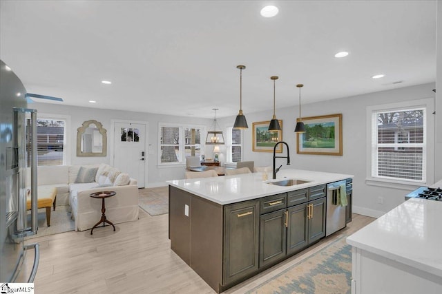 kitchen with pendant lighting, sink, a kitchen island with sink, dark brown cabinetry, and stainless steel dishwasher