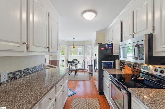 kitchen featuring crown molding, stainless steel appliances, hanging light fixtures, and white cabinets