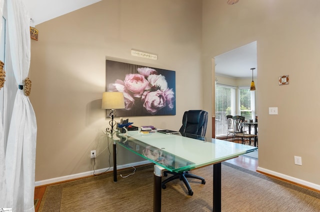 office with wood-type flooring and high vaulted ceiling