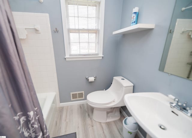 full bathroom with hardwood / wood-style flooring, sink, shower / bath combination with curtain, and toilet