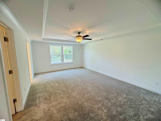 spare room with ceiling fan, a tray ceiling, and carpet floors