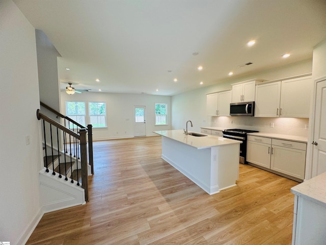 kitchen with electric stove, sink, white cabinetry, and light wood-type flooring