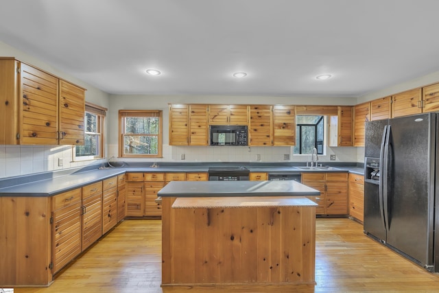 kitchen with sink, black appliances, light hardwood / wood-style floors, and a kitchen island