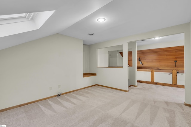 additional living space with vaulted ceiling with skylight and light carpet