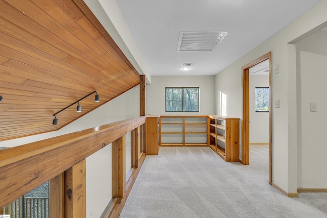 hallway featuring rail lighting, light colored carpet, and wood ceiling