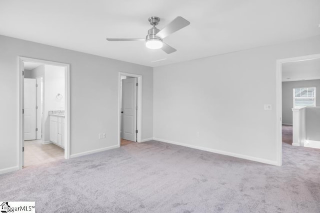 unfurnished bedroom with ceiling fan, ensuite bathroom, and light carpet