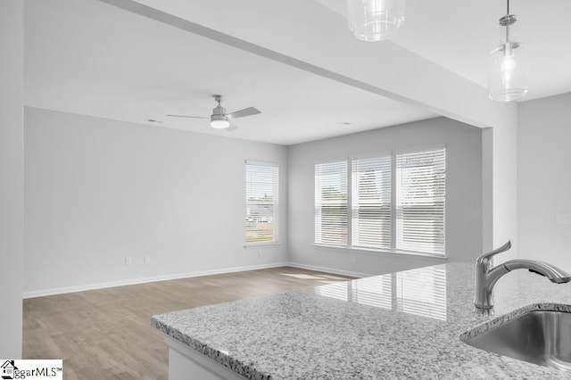 kitchen with light stone counters, decorative light fixtures, and sink