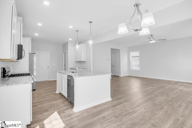 kitchen featuring an island with sink, white cabinets, and decorative light fixtures