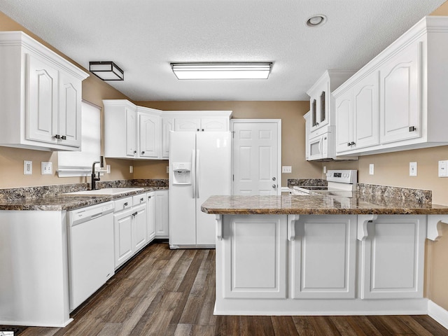 kitchen featuring white cabinetry, sink, white appliances, and kitchen peninsula