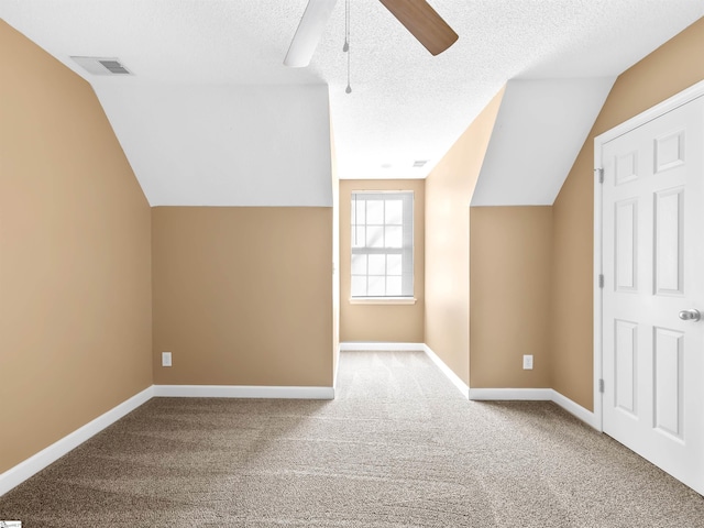 additional living space featuring ceiling fan, lofted ceiling, carpet, and a textured ceiling